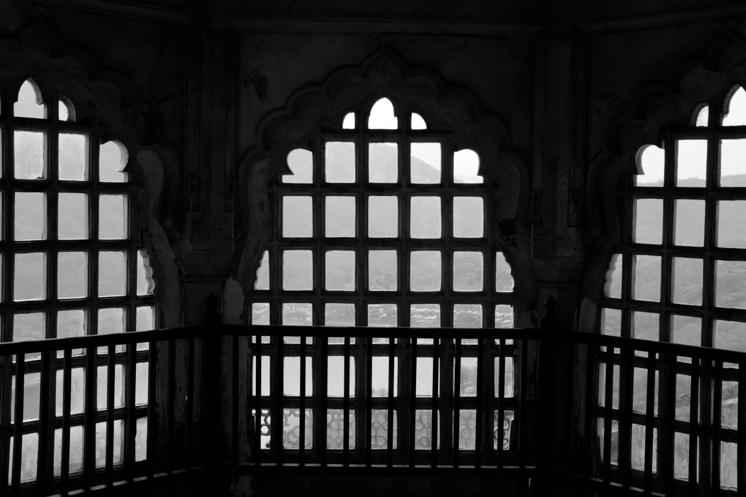 Arched windows with geometric lattice screens framing daylight